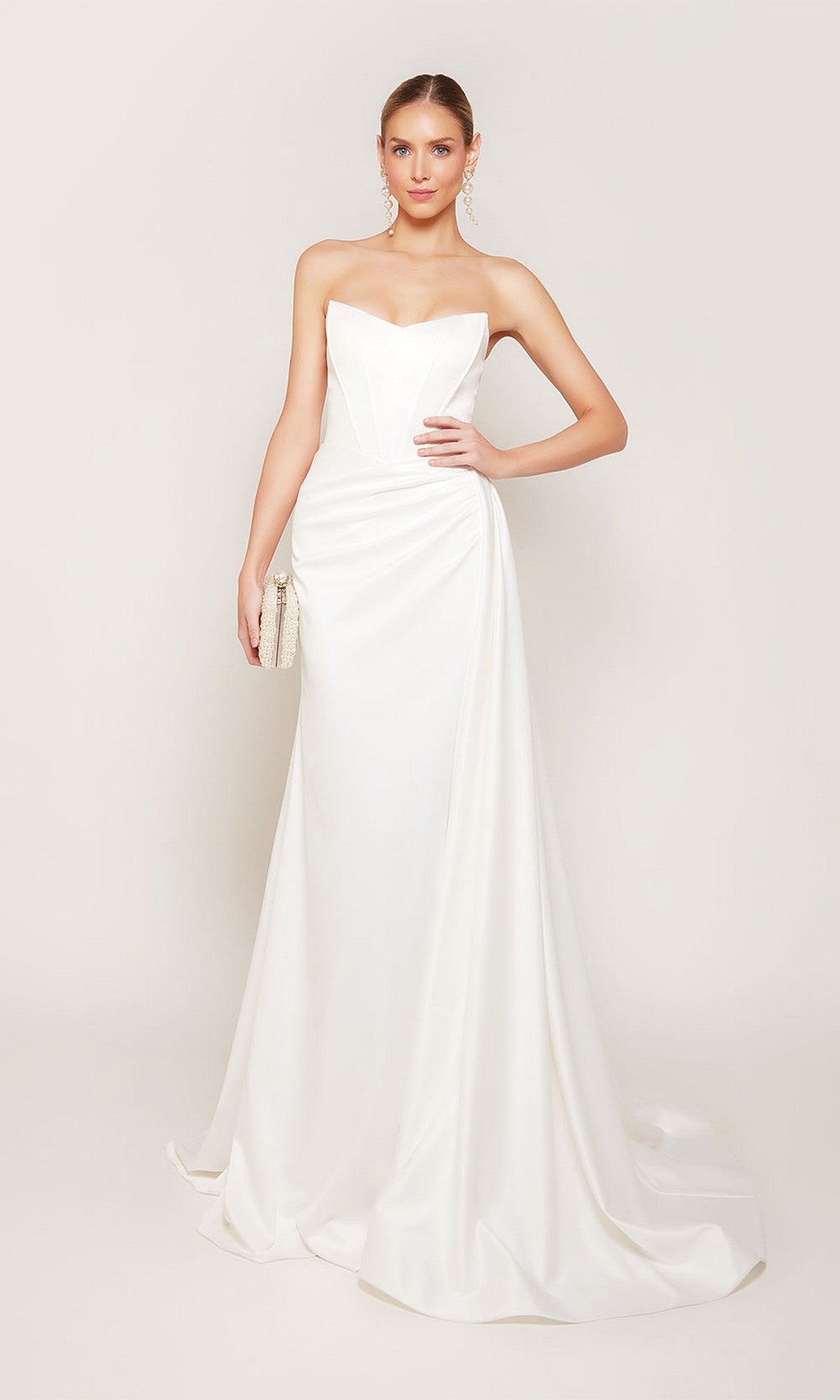 A woman wears the Alyce 7093 long formal dress—a strapless satin gown with a fitted silhouette and slight train—while holding a small clutch against a plain background.